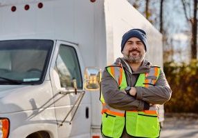 smiling-truck-driver-with-arms-crossed-on-parking-2023-11-27-04-56-27-utc